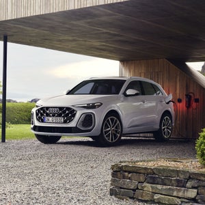 Een Q5 e-hybrid staat op te laden onder de carport van een modern huis.