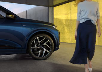 An Audi SQ8 parked elegantly in front of a modern building, showcasing its sleek design and luxury features while vehicle is being charged.