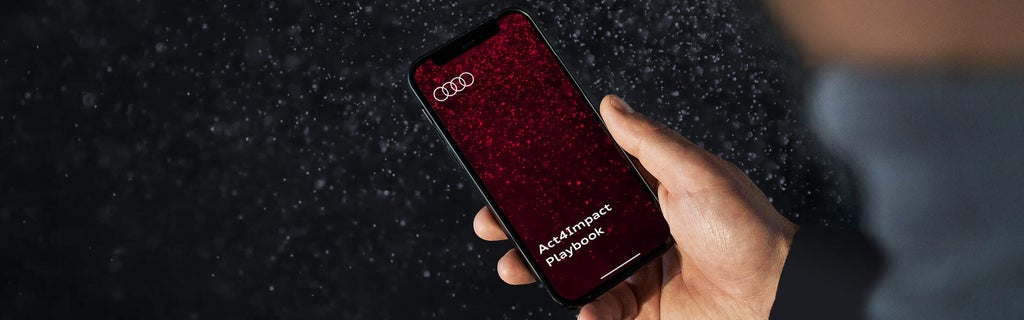 One hand holds a smartphone with a red background. It says Act4Impact Playbook under the Audi logo.