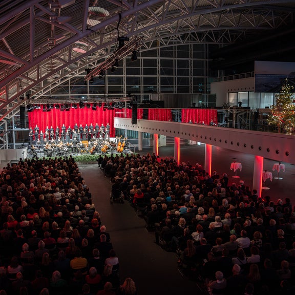 Bird's eye view of a sold-out event hall at the Audi Forum Ingolstadt. A Christmas tree can be seen on the right-hand side.