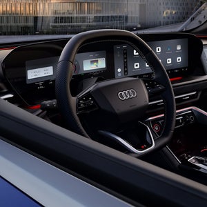 Blick durch das Fahrerfenster in das Cockpit des SQ5 SUV. Im Fokus stehen das Lenkrad mit dem dahinter befindlichen Audi virtual Cockpit, sowie das MMI touch-Display.