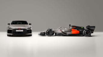The Audi RS 5, shown from the front, stands side-by-side with the Audi R26 race car from the Audi Revolut F1® Team, shown in profile.