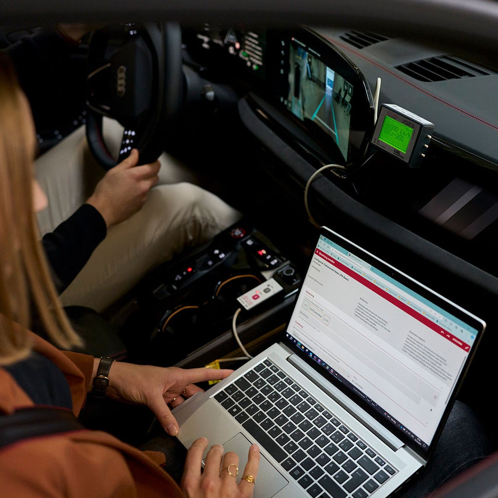 Sophia Schupritt sits in the passenger seat of an Audi with a laptop on her lap
