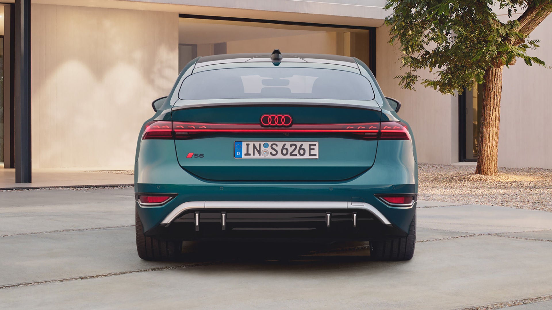 The rear view of a teal Audi S6 Sportback e-tron showcases its sleek design, distinctive taillights, and modern features against a minimalist background.