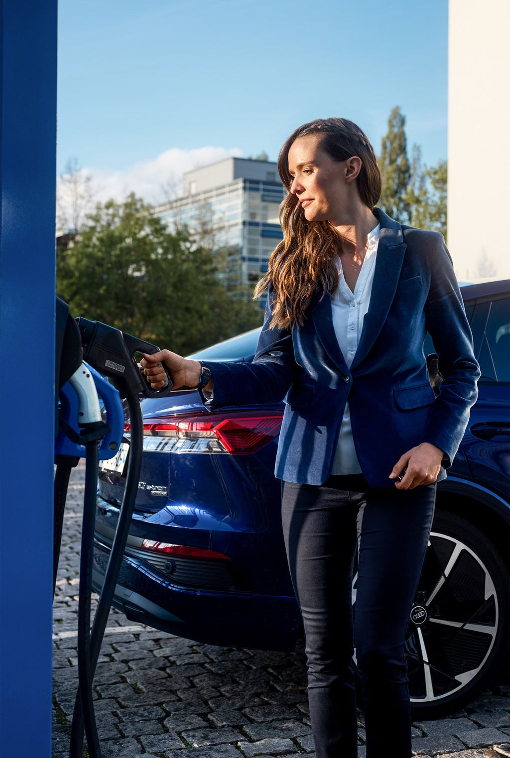 Sunnie Groeneveld an der Ladesäule, im Hintergrund ihr Audi Q4 Sportback e-tron.
