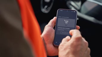 Ein Handy, gehalten von Männerhänden, auf dem in der myAudi App um Hilfe gebeten wird.