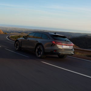 Der Audi A6 allroad schräg von hinten durchfährt eine langgezogene Kurve auf einer Landstraße.