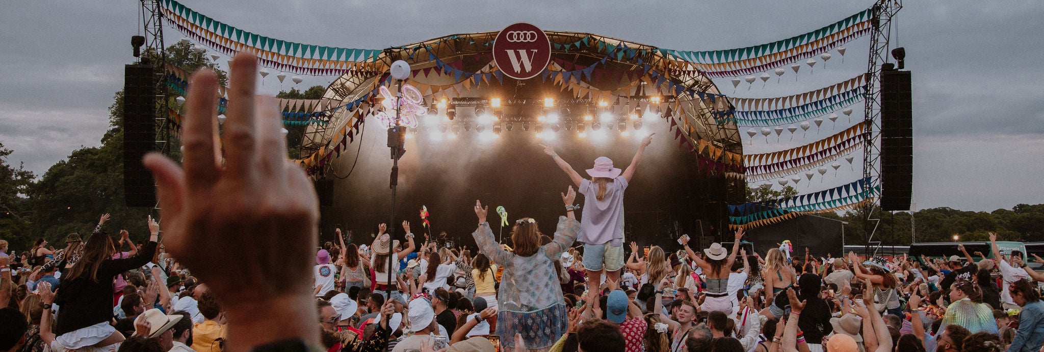 Group of people at an outdoor festival with a sunset background.