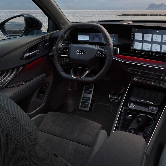 Audi Q3 interior with steering wheel, digital cockpit, infotainment touchscreen, ambient lighting, and sea view.
