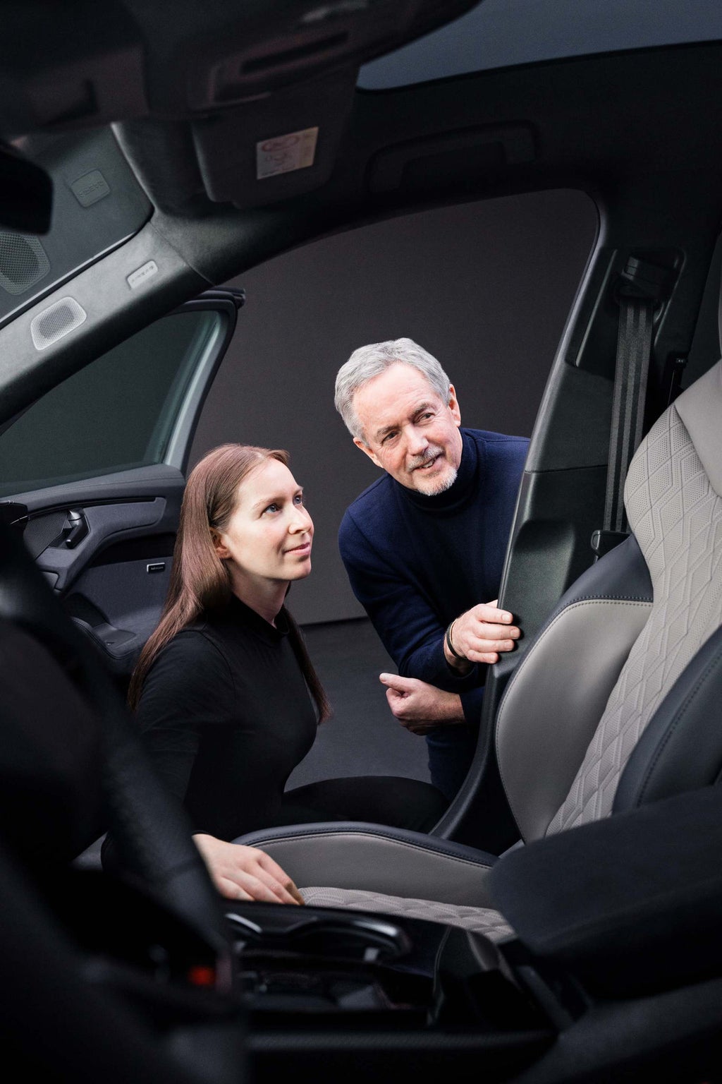 Annika Stößl und Trevor Hill blicken in den Innenraum des Audi A6 Avant und blicken auf den Beifahrersitz.