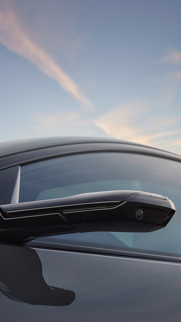 An Audi electric vehicle driving on a scenic mountain road at sunset