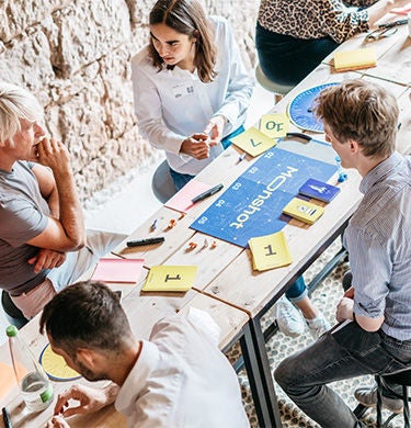 Personen sitzen zusammen an einem Tisch und arbeiten
