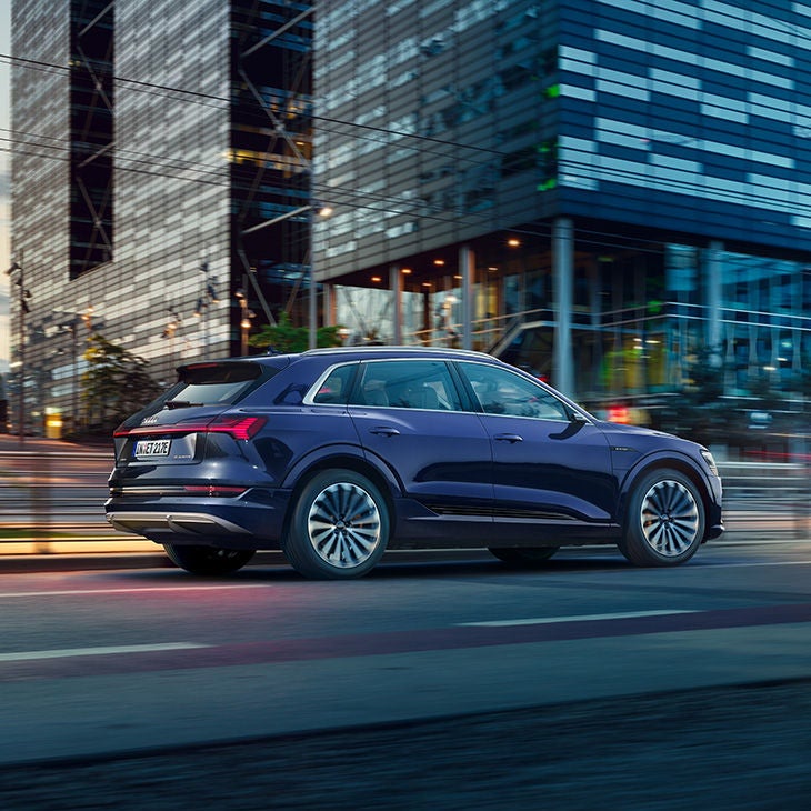 Ein dunkel blauer Audi fährt auf einer Straße in der Großstadt.