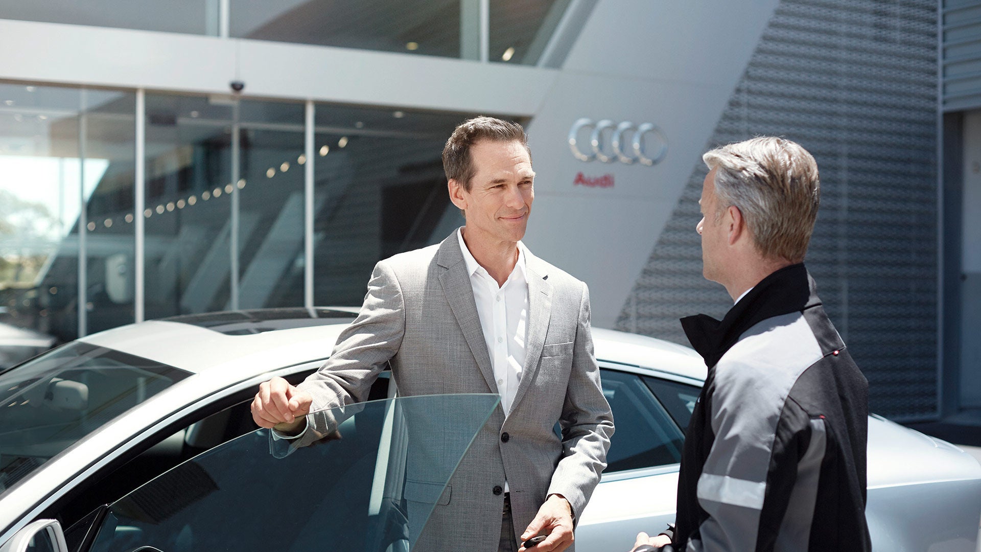 Two men standing by an Audi car