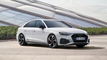 White Audi vehicle parked in front of a modern building with geometric facade