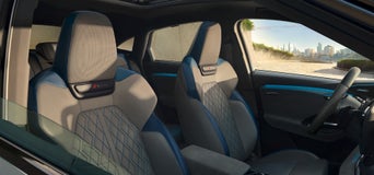 Zwei vordere Sportsitze im Audi Q6 Sportback e-tron mit grauer und blauer Lederpolsterung und S-Logo, Blick nach außen auf die Skyline.