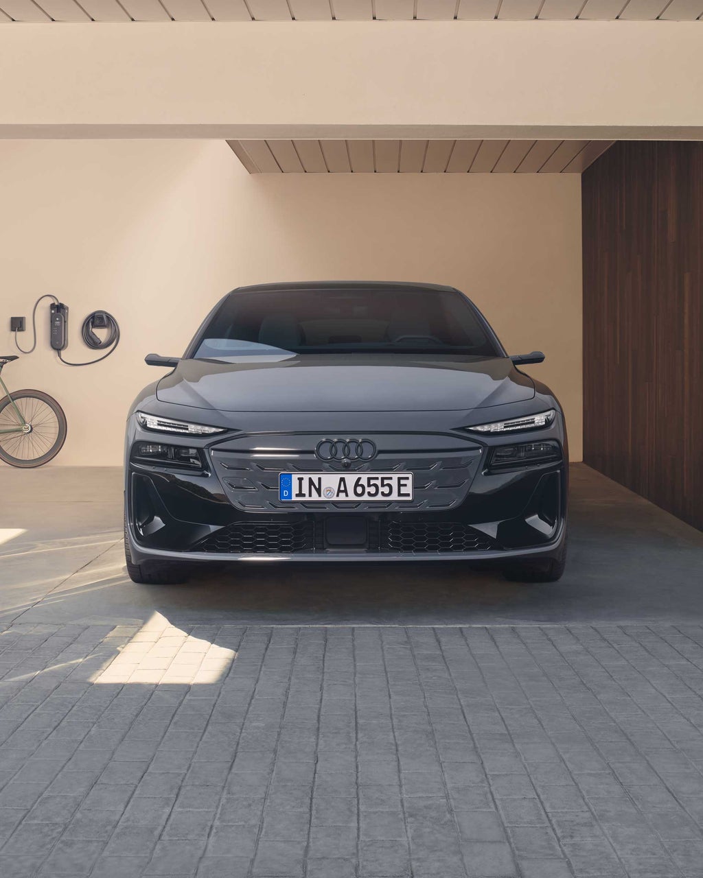 Grauer Audi A6 Avant e-tron steht frontal in Garage mit Wallbox und Fahrrad.
