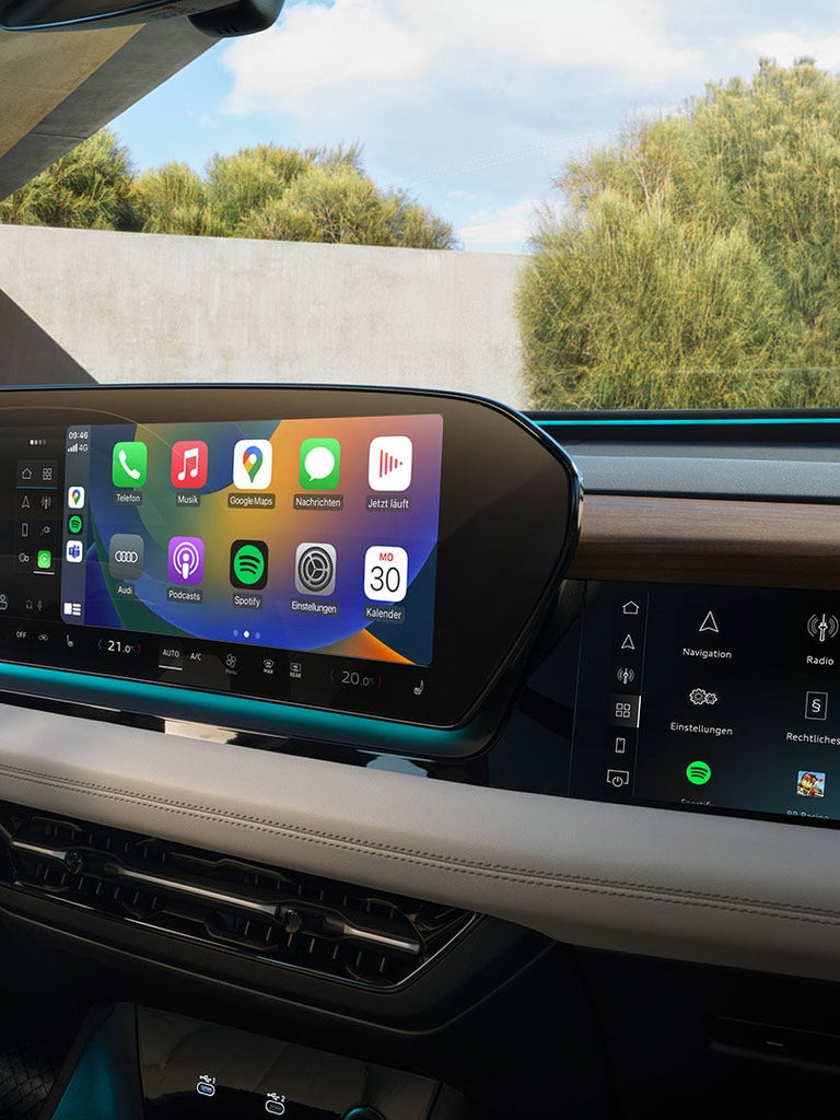 Großes Zentraldisplay eines Audi Q6 SUV e-tron zeigt Apps von Apple CarPlay mit farbiger Benutzeroberfläche.