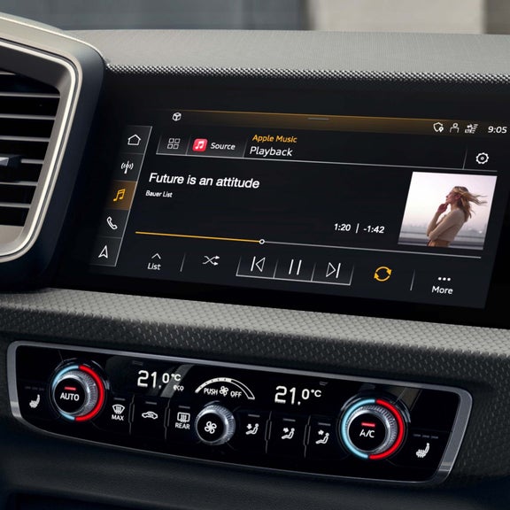 Audi A1 Sportback car infotainment screen displaying music player and climate controls below.