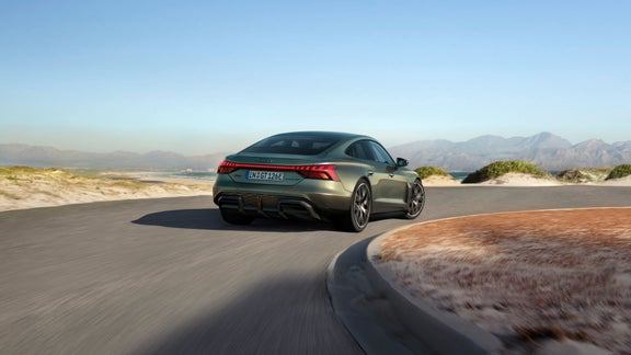 En olivgrön RS e-tron GT Performance sedd bakifrån, på en väg i ett ökenlandskap