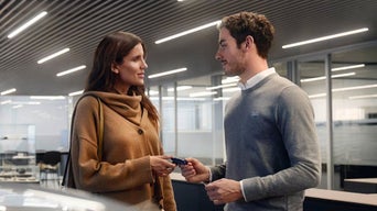 Audi Mitarbeiter übergibt Autoschlüssel an Kundin im Autohaus.