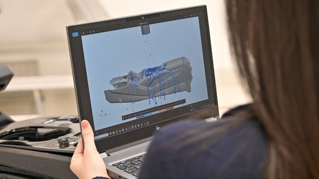 Person betrachtet auf einem Laptop die Simulation eines Wasserversuchs an einem Fahrzeugbauteil.