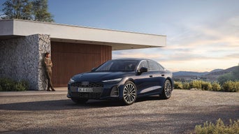 Ein Mann ist an eine Hauswand gelehnt und ein blauer A6 steht davor