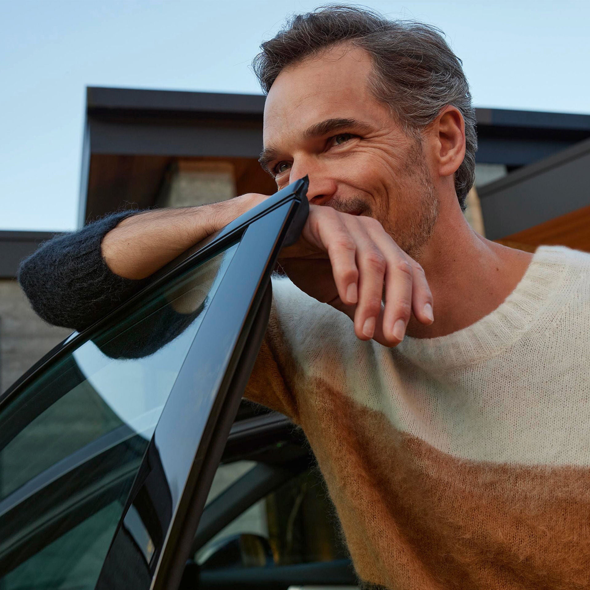 Mann lehnt an Autotür