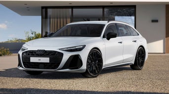 The A6 Avant in the black edition one with a sloping front profile, parked in front of a modern residential building.