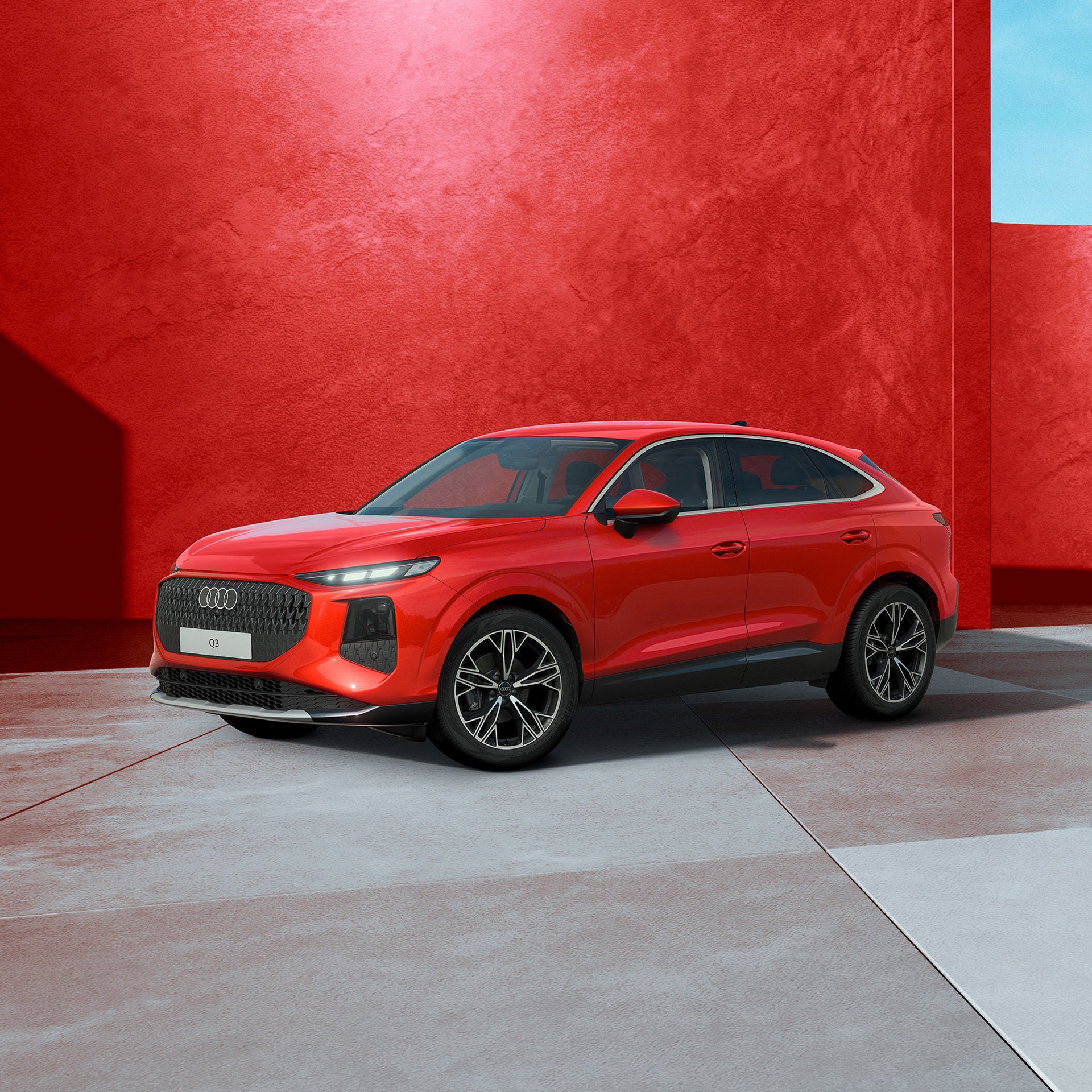 Ein roter Audi Q3 Sportback von seitlich vorne fotografiert vor einer modernen Kulisse.