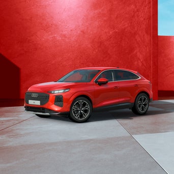 Ein roter Audi Q3 Sportback von schräg vorne fotografiert vor einer modernen Kulisse.