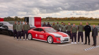 The soccer players of FC Bayern Munich pose on a racetrack next to Audi vehicles.