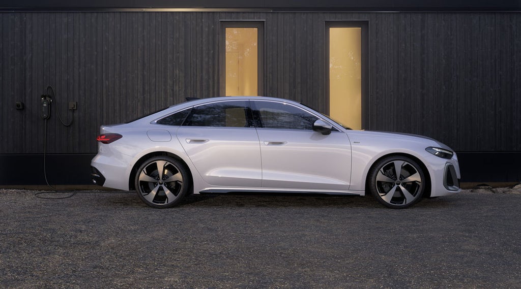 De A5 Limousine e-hybrid in zijprofiel voor een gebouw met houten gevel.