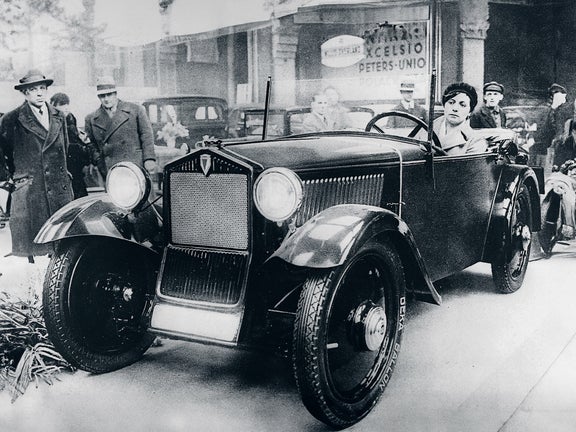 Black and white photo of a woman driving the DKW Front F 1, surrounded by people