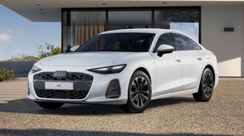 The A6 Saloon e-hybrid with its sloping front profile, parked in front of a modern residential building.