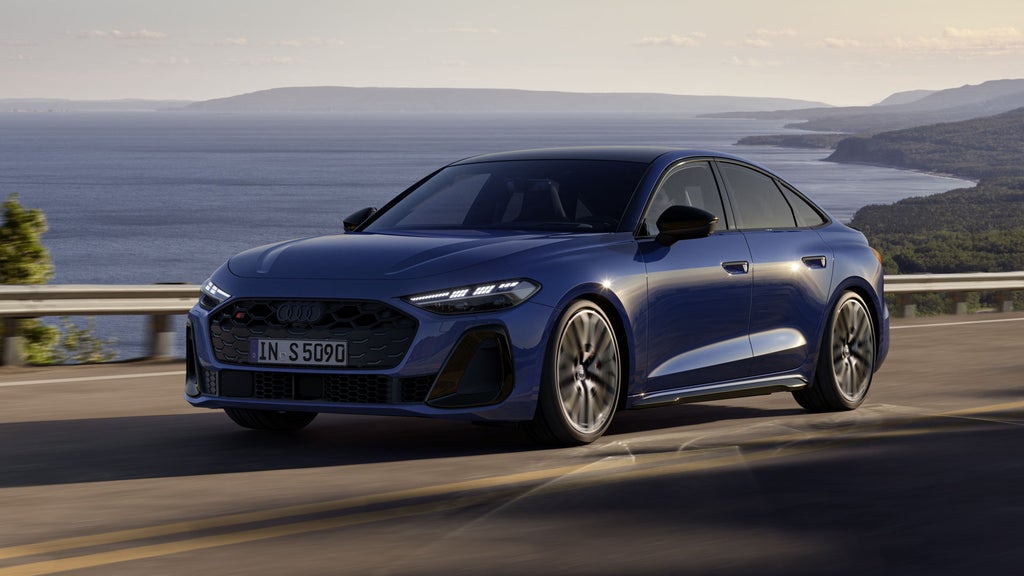 Die S5 Limousine in dunkelblau fährt auf einer Straße entlang der Küste.