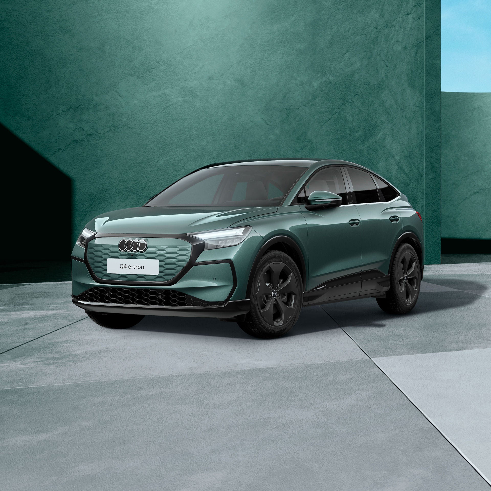 Ein salbeigrün metallischer Audi Q4 Sportback e-tron von schräg vorne fotografiert vor einer modernen Kulisse.
