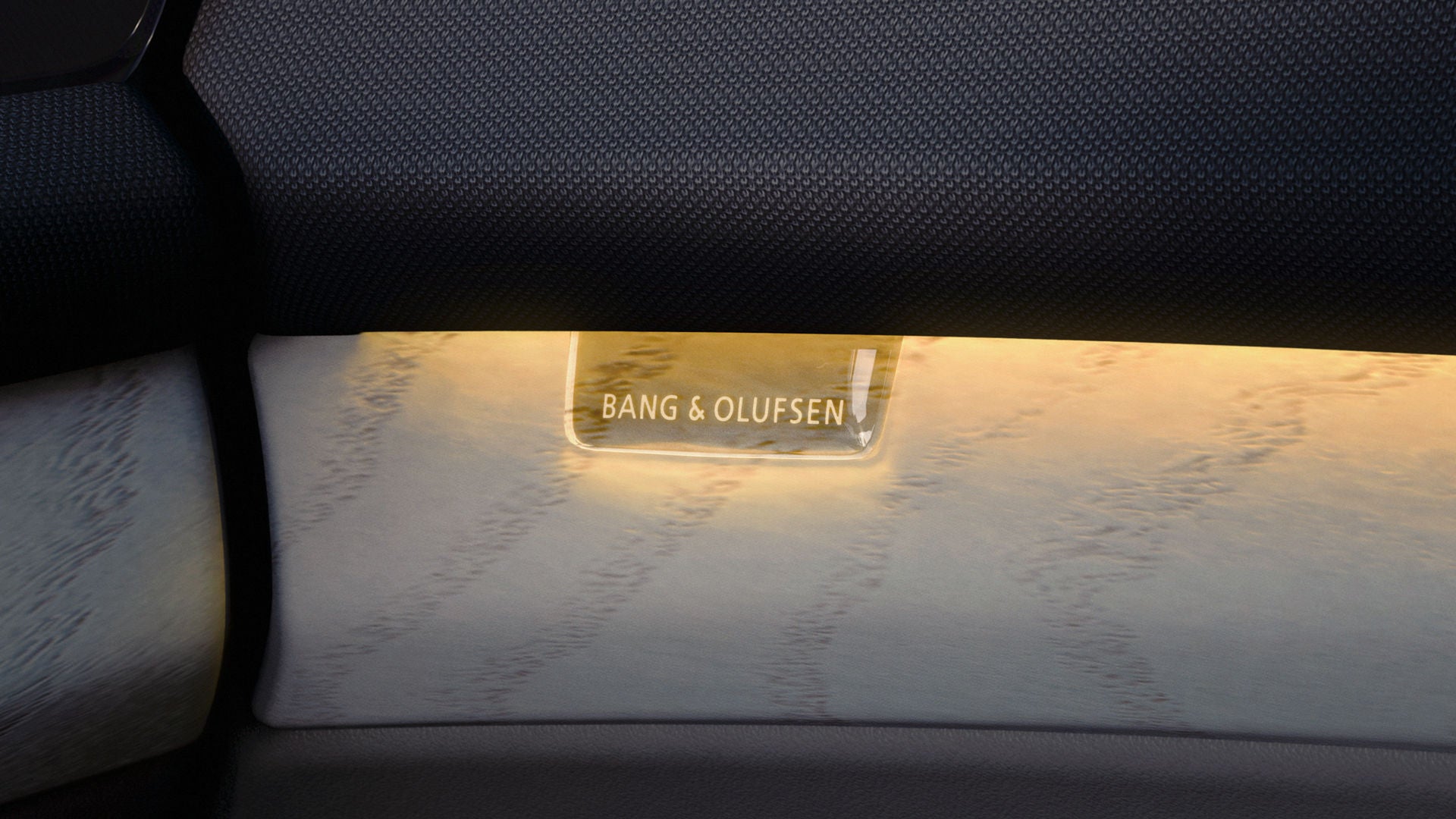 Nahaufnahme des Bang & Olufsen Logos, beleuchtet vom gelblichen Interaktionslicht.