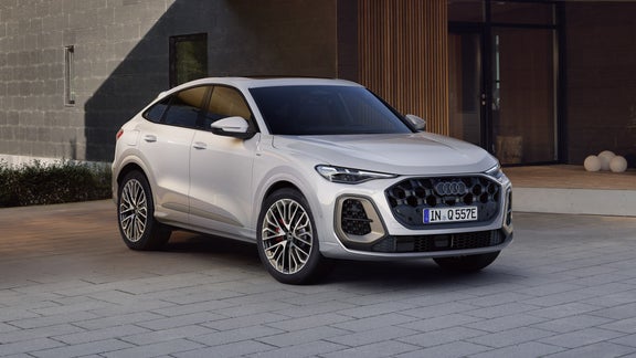 Die weiße Edition One mit magnesiumgrauen Akzenten des Q5 Sportback e-hybrid parkt vor einem modernen Haus.