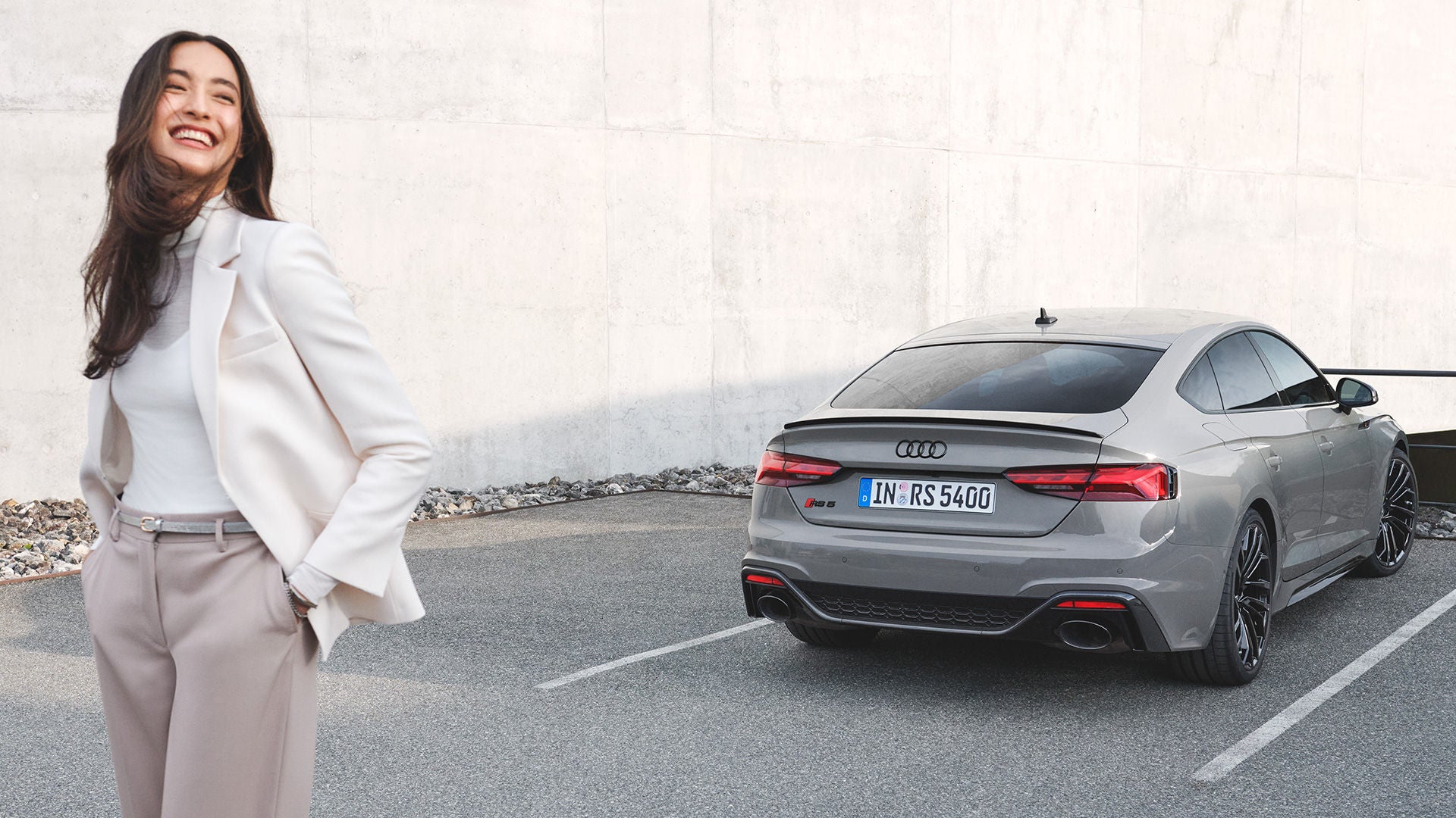 Kvinna som står bakom en silvrig Audi RS 5 och ler