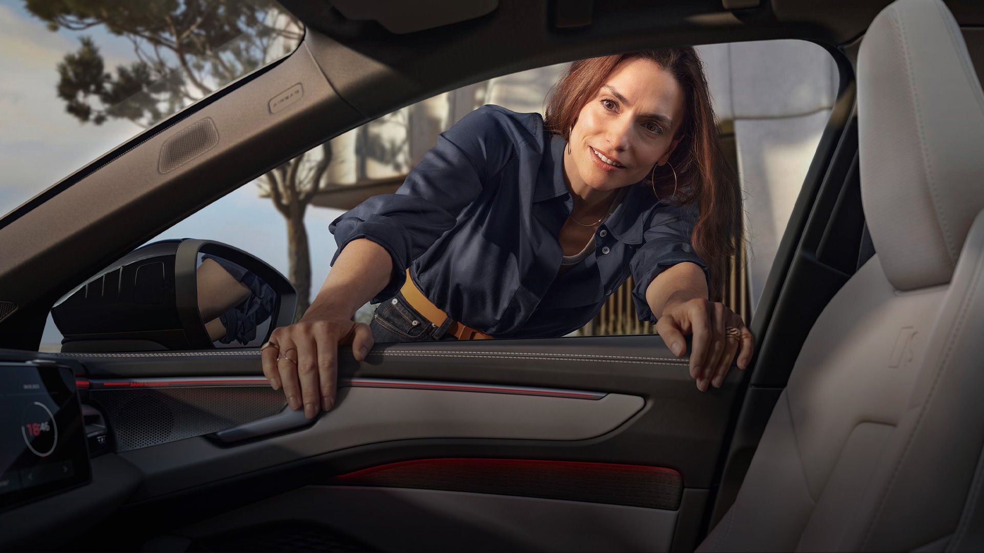 Frau beugt sich freundlich lächelnd durch das offene Fenster eines geparkten Audi, mit Blick ins Fahrzeuginnere.