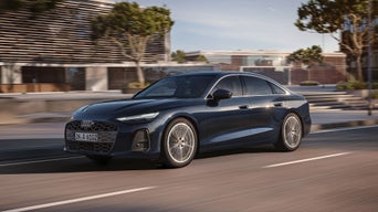 Blaue Audi A6 Limousine fährt auf einer Straße durch die Stadt.