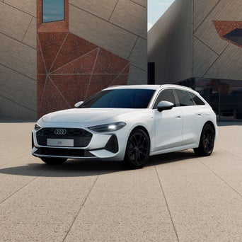 Ein weißer A5 Avant e-hybrid steht vor einem weißen Gebäude