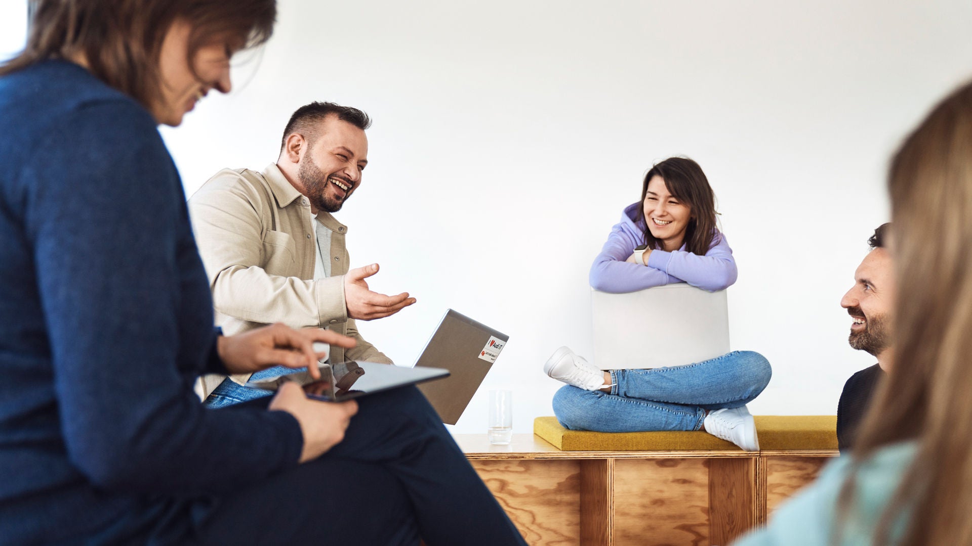 Fünf Personen sitzen im Kreis und lachen miteinander