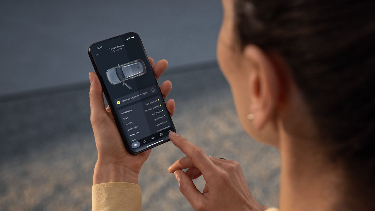 Frau hält Handy in der Hand. In der unteren linken Ecke befindet sich ein QR Code zur myAudi App