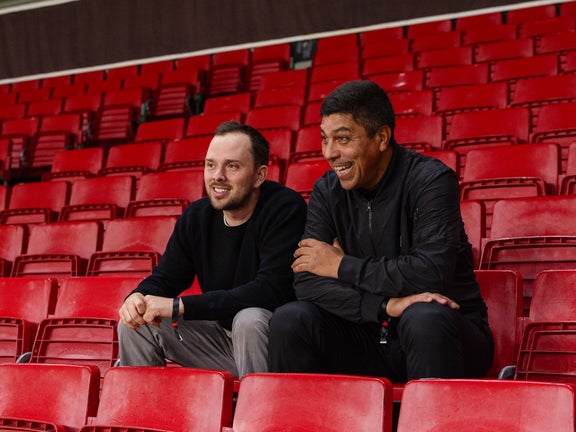 Zwei Männer sitzen im Stadion und lachen