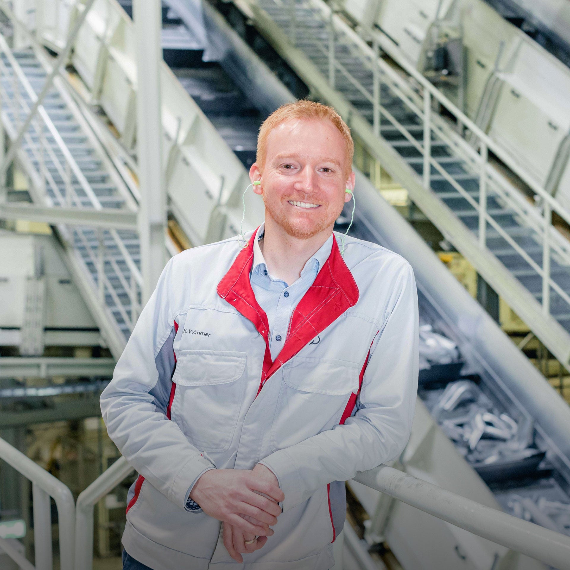 Porträt von Heiko Wimmer, Leiter Instandhaltung Presswerk Audi Neckarsulm, in Werkhalle mit Förderanlagen im Hintergrund. 