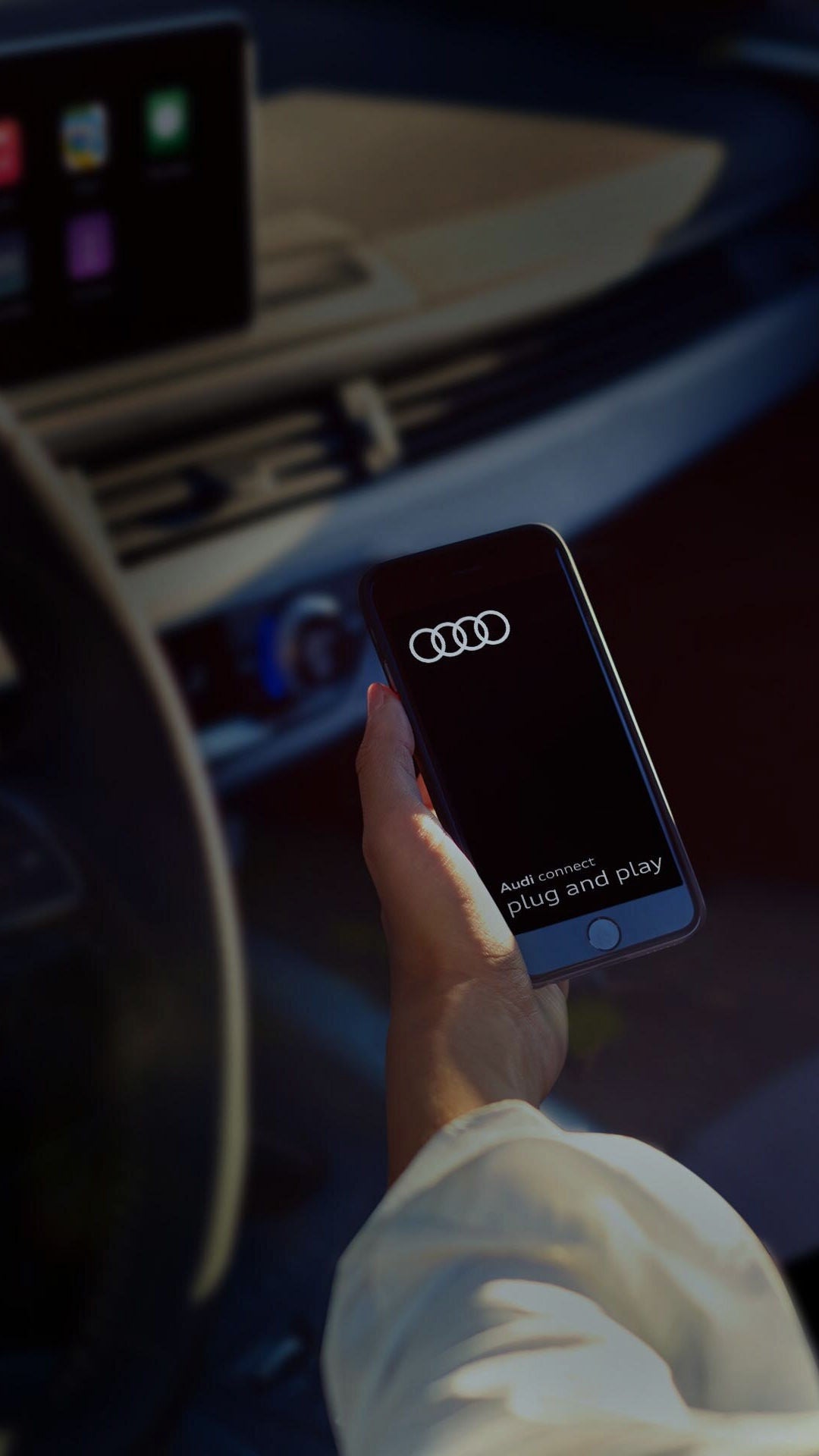 A hand picking up a phone that was resting in a car console next to the manual gear stick