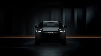 Frontansicht eines schwarzen Audi mit eingeschaltetem LED-Tagfahrlicht, inszeniert in dunkler Umgebung mit dezentem Lichtstreifen.