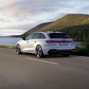 A5 Avant e-hybrid sedd från en sned bakifrånperspektiv när den kör längs en väg vid en sjö.